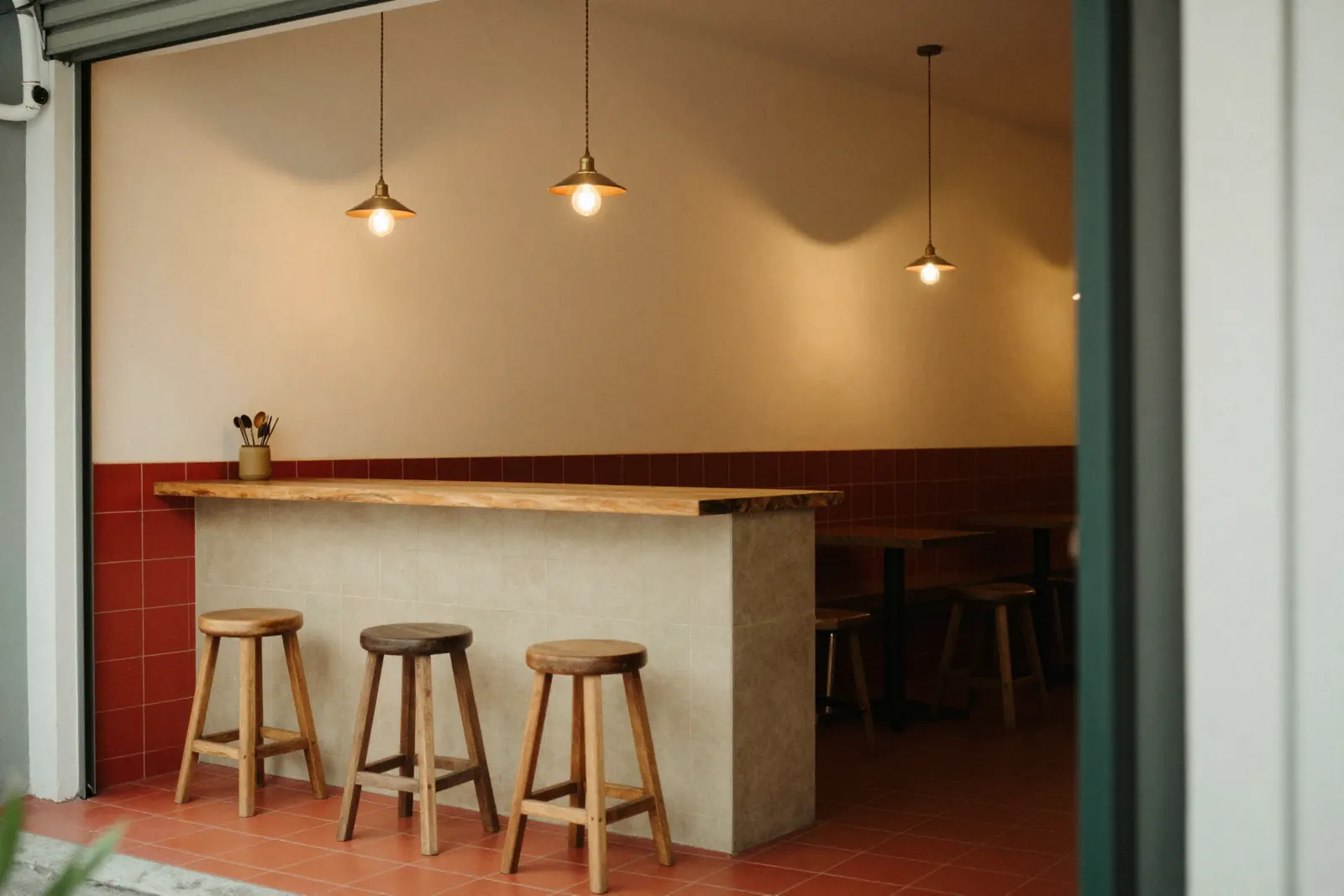 A cosy cafe counter with cream and red tiles and wooden stools